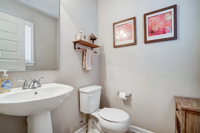 bathroom with toilet, baseboards, and a sink