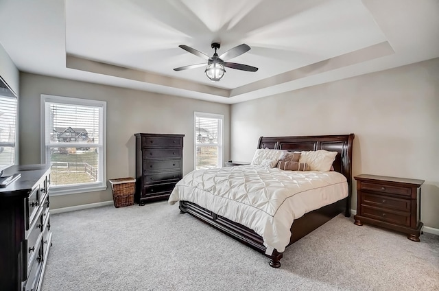 bedroom with a tray ceiling, baseboards, carpet floors, and ceiling fan