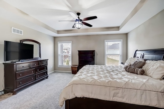 bedroom featuring a raised ceiling, baseboards, visible vents, and light carpet