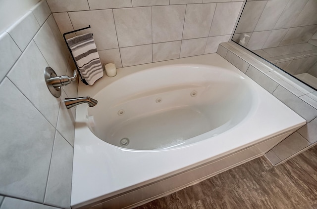 bathroom with a tub with jets and wood finished floors