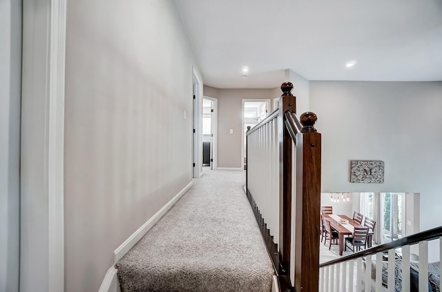 hall featuring light colored carpet and baseboards