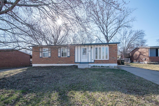 view of front of property with a front yard, brick siding, and driveway