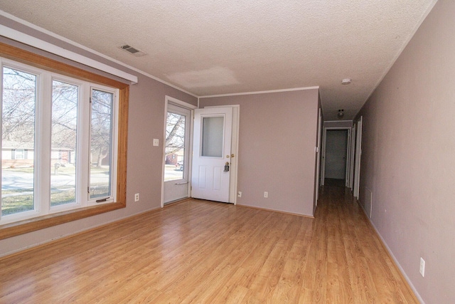 unfurnished room featuring a healthy amount of sunlight, visible vents, light wood finished floors, and a textured ceiling