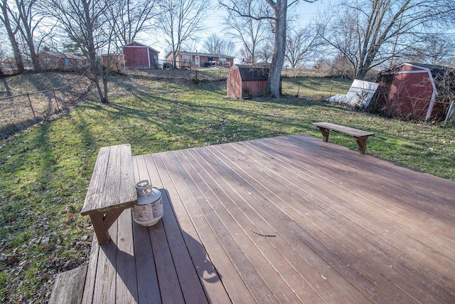 wooden deck featuring a shed, a lawn, an outdoor structure, and fence