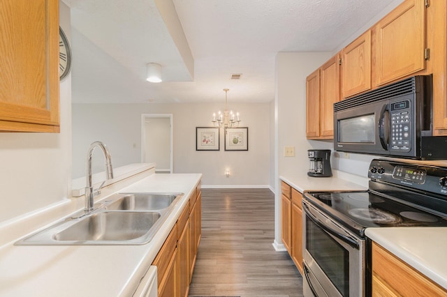 kitchen with black microwave, light countertops, stainless steel range with electric stovetop, wood finished floors, and a sink