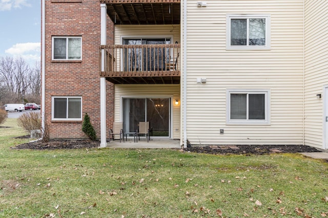 back of property featuring a yard, a patio, and a balcony