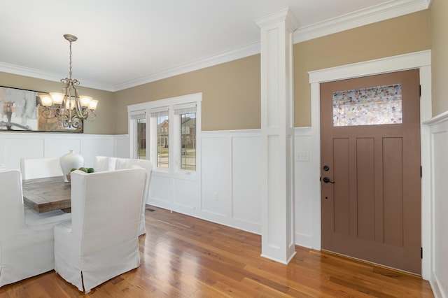 dining area with light wood finished floors, an inviting chandelier, and ornamental molding