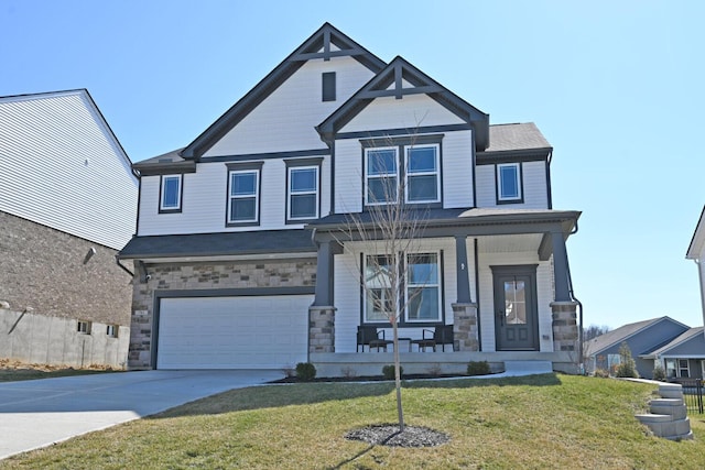 view of front facade featuring a porch, a front yard, driveway, stone siding, and an attached garage