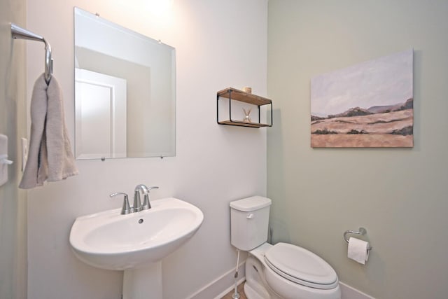 bathroom featuring toilet, baseboards, and a sink