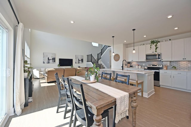 dining area with recessed lighting, stairway, and light wood-style floors