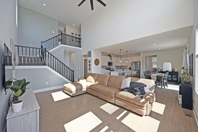 living room with baseboards, stairway, recessed lighting, a towering ceiling, and wood finished floors