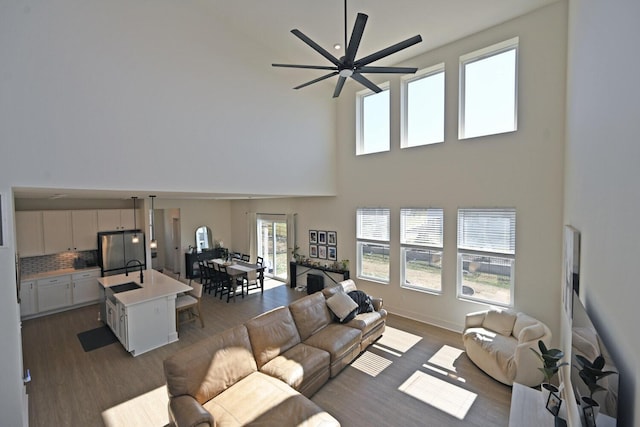 living room with dark wood-type flooring, a ceiling fan, and a towering ceiling