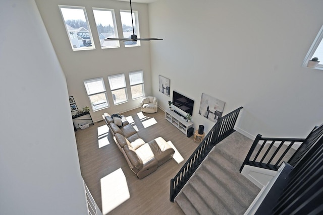 living room with plenty of natural light, wood finished floors, and a towering ceiling