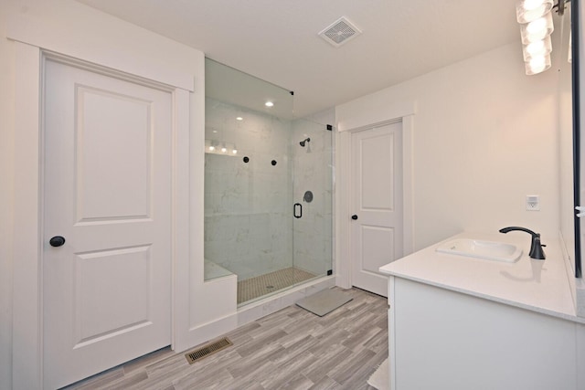 bathroom with vanity, a shower stall, wood finished floors, and visible vents