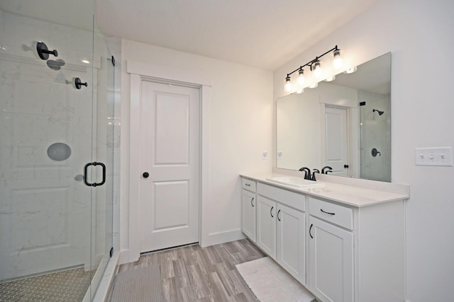 bathroom featuring a stall shower, vanity, baseboards, and wood finished floors