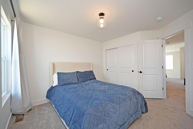 carpeted bedroom with a closet, baseboards, and visible vents