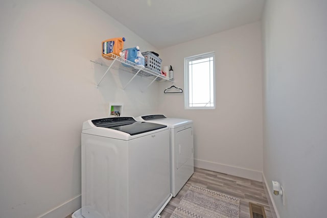 washroom with visible vents, independent washer and dryer, light wood-style floors, baseboards, and laundry area