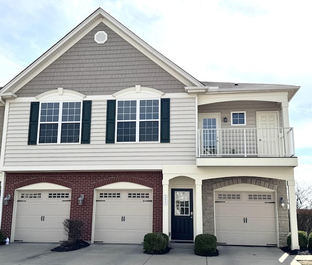 view of front facade featuring concrete driveway, a balcony, brick siding, and a garage