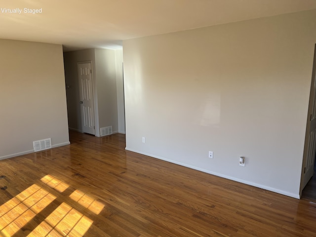 empty room featuring visible vents, baseboards, and wood finished floors