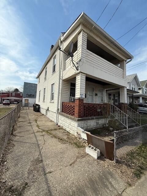 view of side of property with a porch, fence, and a chimney