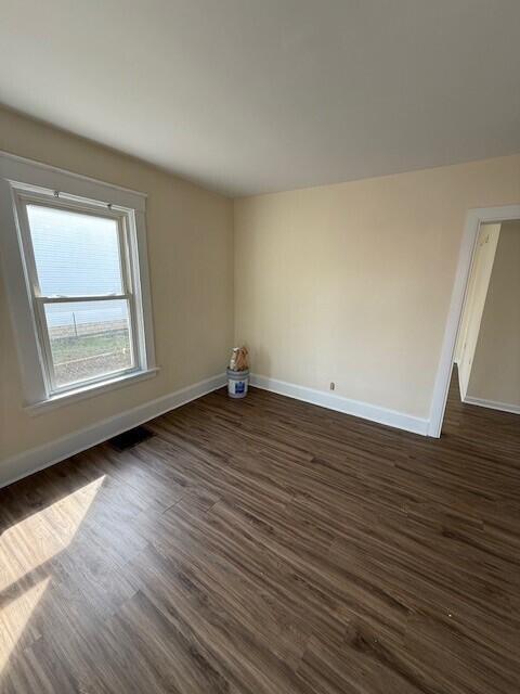 spare room featuring dark wood finished floors and baseboards