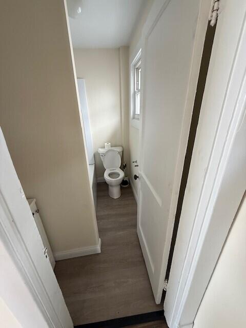 bathroom with baseboards, toilet, and wood finished floors