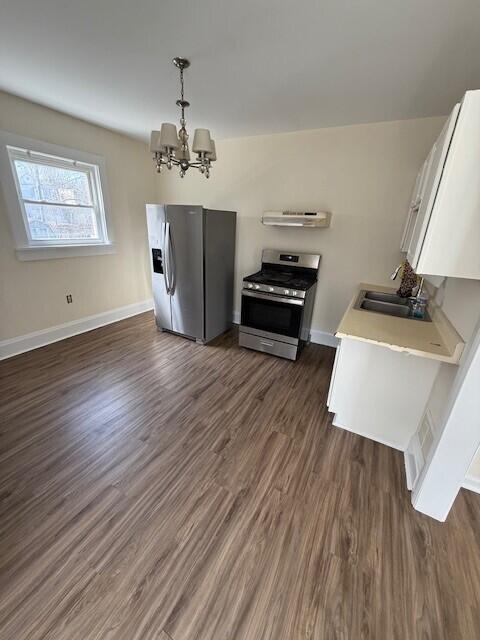 kitchen featuring dark wood-style flooring, a sink, stainless steel appliances, white cabinets, and a chandelier