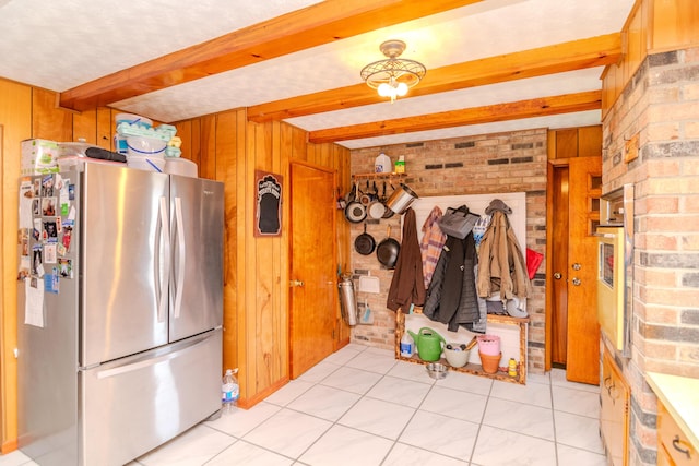 kitchen with beam ceiling, wooden walls, brick wall, and freestanding refrigerator