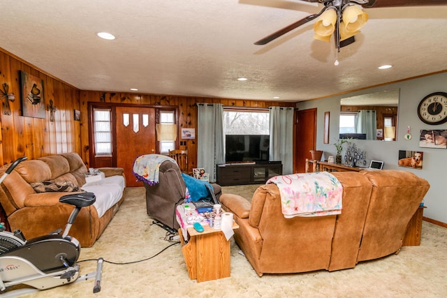 living room with a textured ceiling, a healthy amount of sunlight, wood walls, and ornamental molding