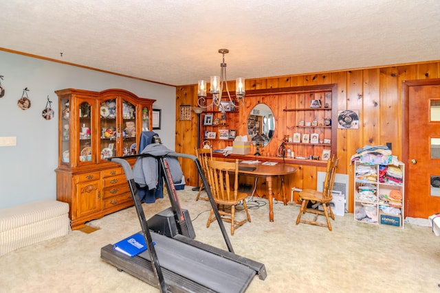 exercise area with carpet floors, a textured ceiling, a chandelier, and ornamental molding