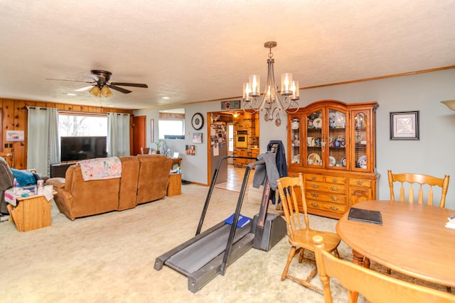 workout room featuring a textured ceiling, light colored carpet, crown molding, and ceiling fan with notable chandelier