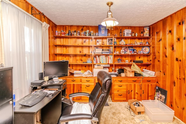 home office with a textured ceiling, wood walls, and carpet