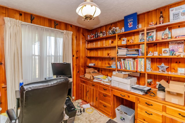 home office featuring wooden walls and a textured ceiling