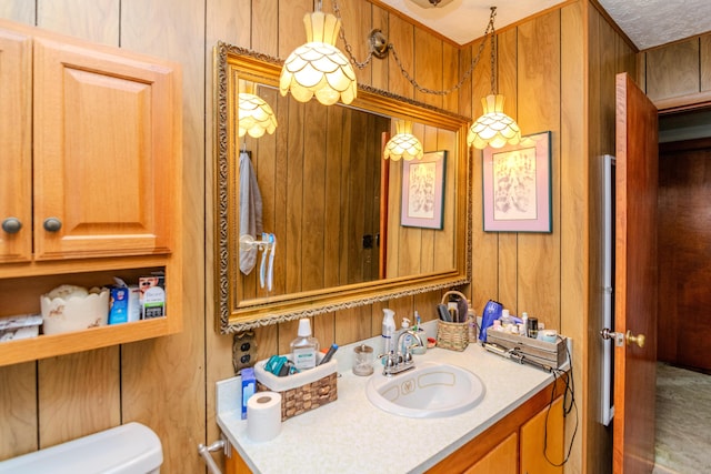 bathroom featuring wooden walls, vanity, and toilet