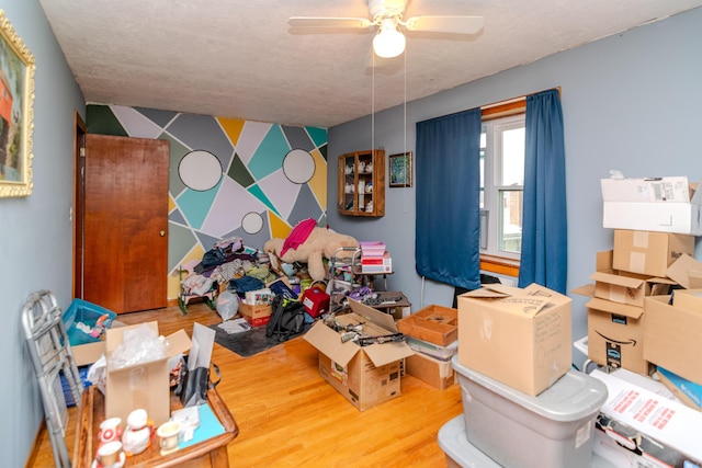 interior space featuring wood finished floors, wallpapered walls, ceiling fan, a textured ceiling, and an accent wall