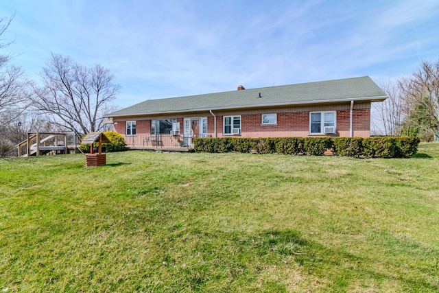 rear view of house featuring a deck, a lawn, and brick siding