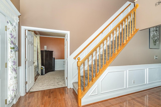 stairs featuring a decorative wall, wood finished floors, and wainscoting