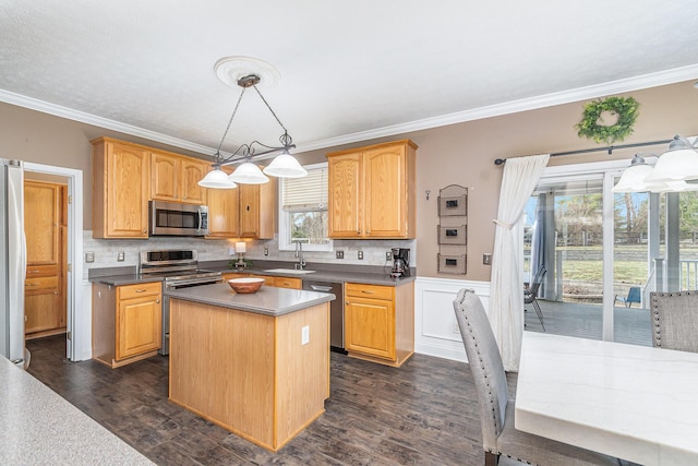 kitchen with dark wood finished floors, crown molding, appliances with stainless steel finishes, and a kitchen island