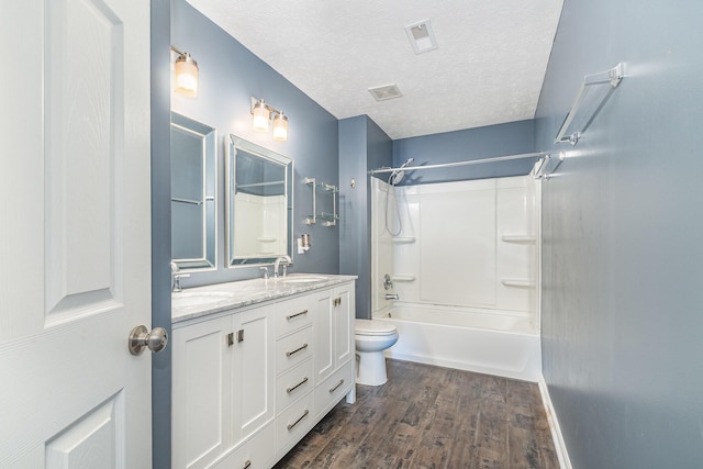 full bathroom with a textured ceiling, toilet, wood finished floors, and a sink