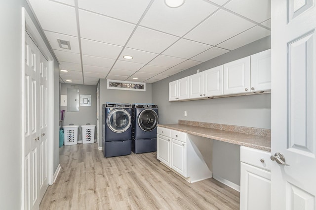 clothes washing area featuring washer and clothes dryer, visible vents, cabinet space, and light wood-style flooring