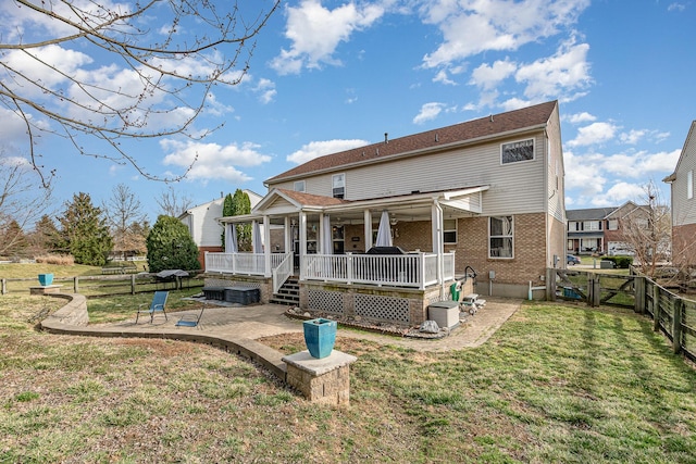 back of house with brick siding, a fenced backyard, a yard, a patio, and a gate