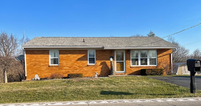 view of front of home featuring brick siding, a shingled roof, and a front yard