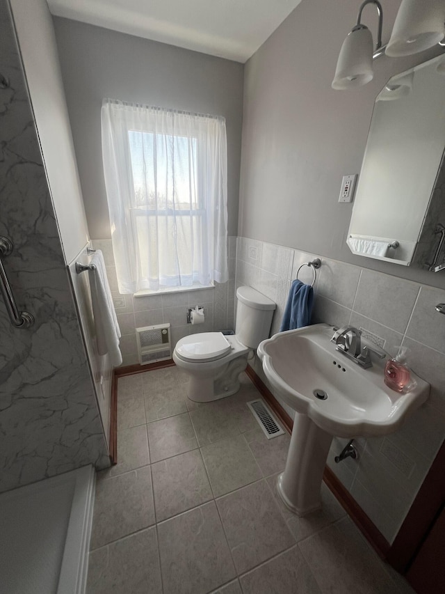 bathroom with visible vents, toilet, wainscoting, tile patterned floors, and tile walls