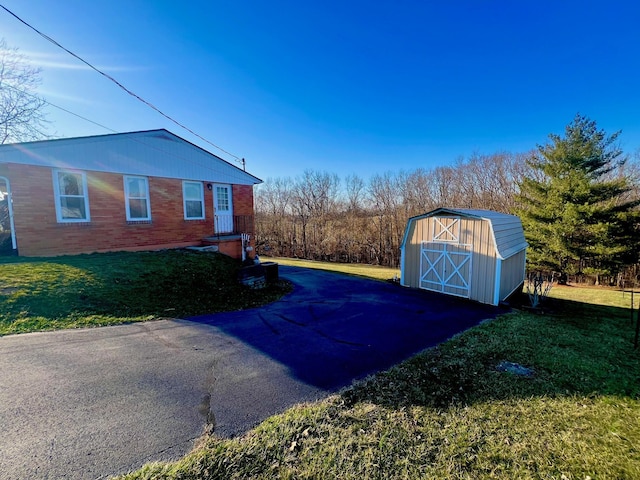 view of side of home with a storage shed, an outdoor structure, a yard, and brick siding