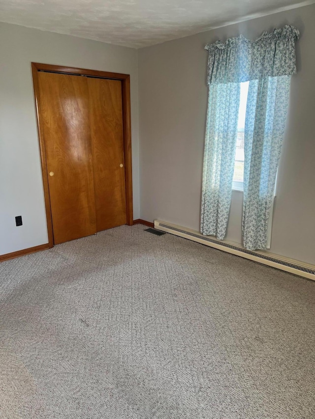 unfurnished room featuring a baseboard radiator, baseboards, and carpet flooring