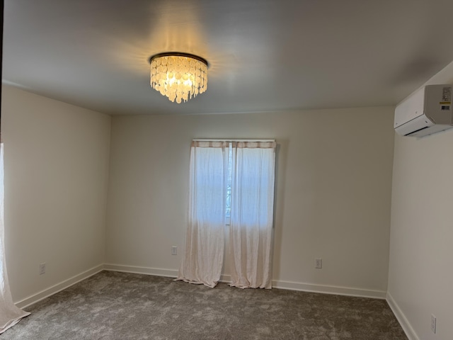 empty room featuring an AC wall unit, a notable chandelier, baseboards, and dark colored carpet