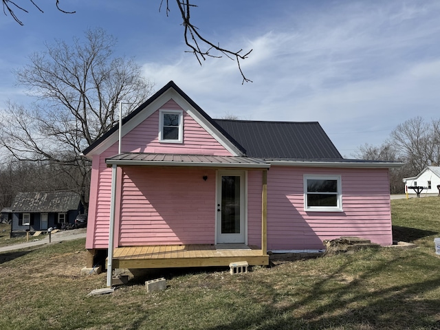 back of property with metal roof and a lawn