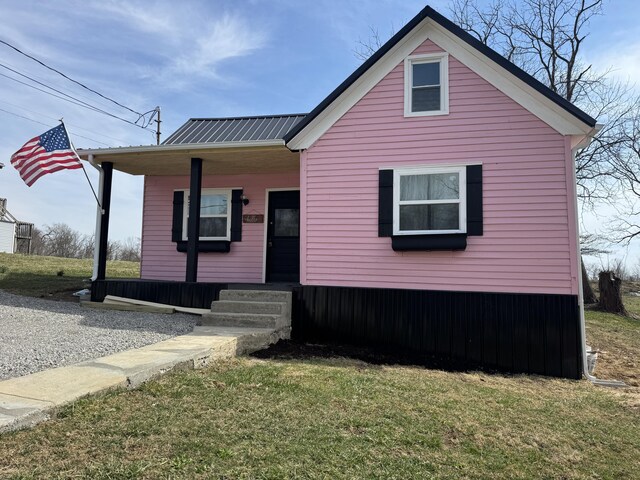 view of front of property with covered porch, metal roof, and a front yard