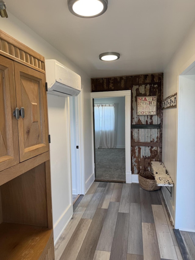 corridor featuring baseboards, an AC wall unit, and wood finished floors