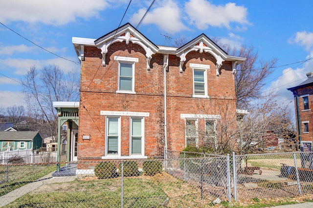 traditional home with a gate, brick siding, and a fenced front yard